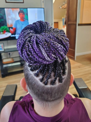 Purple braids tied up in a high bun with shaved sides