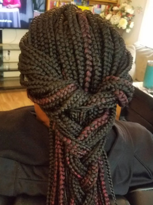 Box braids with red highlights styled in a woven half-updo